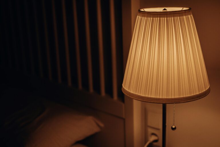 nocna lampka stojąca obok łóżka w przytłumionym świetle